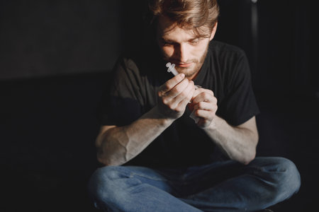 Junkie man holding syringe for drug doseの写真素材