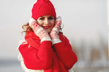Woman in knitted winter hat and scarf looking at camera with smileの写真素材