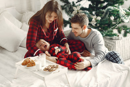 Beautiful family sitting on bed hugging and eating cookies