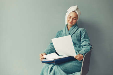 Beautiful girl sitting in a studio in a blue bathrobeの写真素材