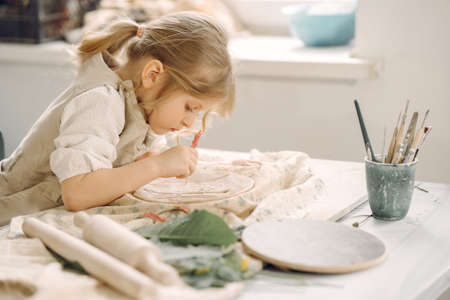 Little girl makes a clay plate and decorates itの写真素材