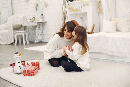 Mother with cute daughter at home with christmas giftsの写真素材
