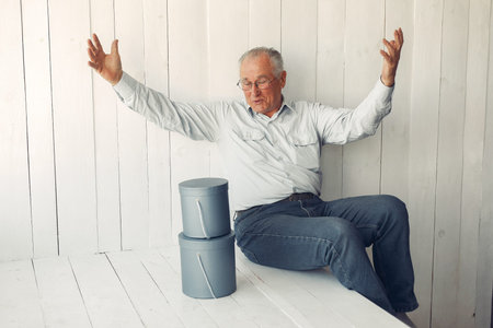 Elegant old man sitting at home with christmas presents