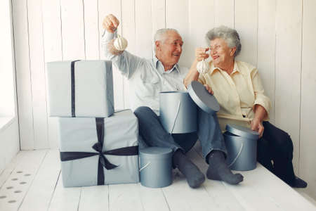 Elegant old couple sitting at home with christmas giftsの写真素材