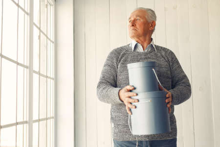 Elegant old man sitting at home with christmas presentsの写真素材