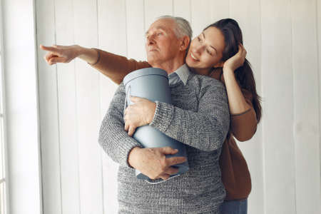 Elegant old man standing at home with his granddaughterの写真素材