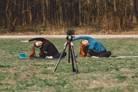 Cute girls doing yoga in a summer parkの写真素材