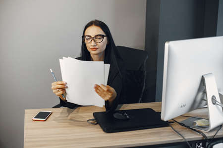 Woman sitting at a desk in the office and reading documents.の写真素材