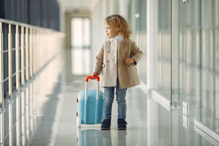 Little girl with a suitcase at the airportの写真素材