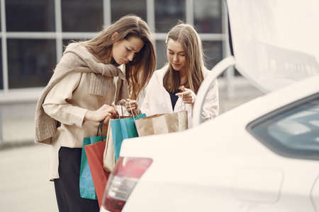Woman standing by the car with shopping bagsの写真素材