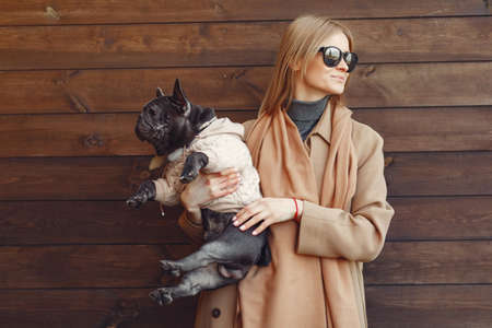 Elegant woman in a brown coat with black bulldogの写真素材