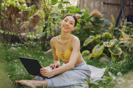 Girl sitting in a summer park and holding a laptop in her hands