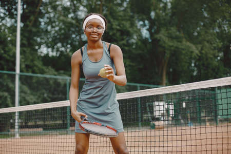Black american female tennis player playing on the court outdoorsの写真素材