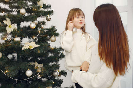 Mother with cute daughter standing near christmas treeの写真素材