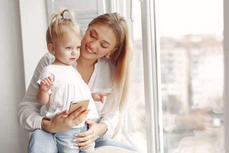 Mother and little daughter spend time together sitting on the windowsill.の写真素材