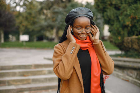 Young black woman in a coat using an earphones outsideの写真素材