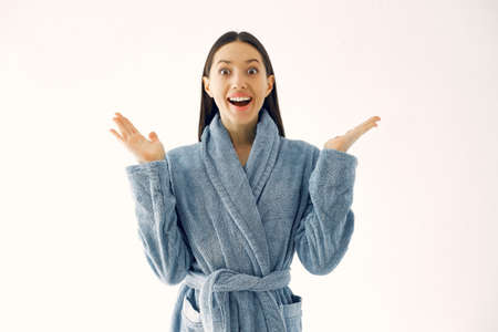 Beautiful girl standing in a studio in a blue bathrobeの写真素材