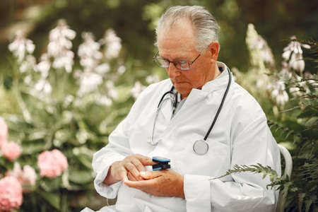 Old doctor sitting at the summer parkの写真素材