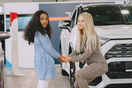 Caucasian mother with african daughter in a car salonの写真素材