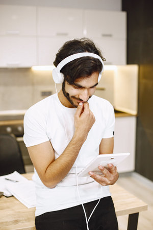 Online education. Young arabic man study with a tablet at home and have an earphones.の写真素材