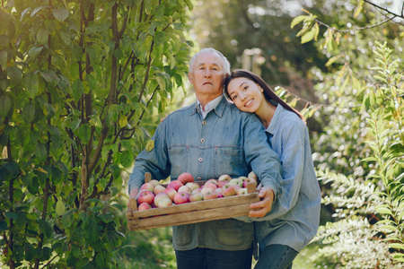 Old senior standing in a summer garden with harvestの写真素材