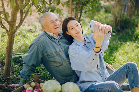 Old senior standing in a summer garden with harvestの写真素材