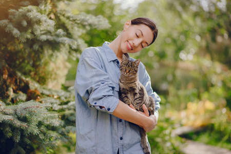 Girl in a blue shirt playing with cute kittyの写真素材