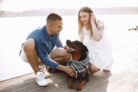 Portrait of a romantic couple with their rotweiller near the lakの写真素材