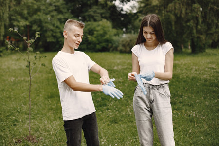 Young volunteers putting on rubber gloves outdoorsの写真素材