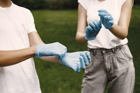 Young volunteers putting on rubber gloves outdoorsの写真素材