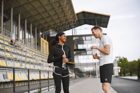 African-american woman and caucasian man talking while training at the stadium