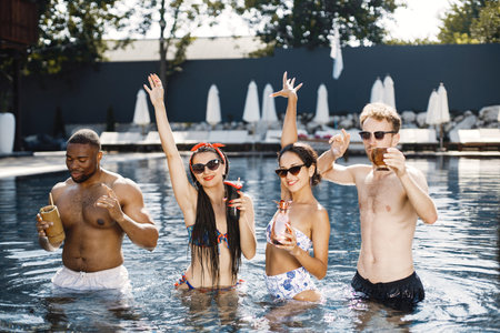 Four friends in a swimwears relaxing in swimming pool