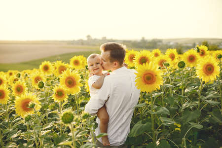 Father hugging his son while standing in the sunflowers fieldの写真素材