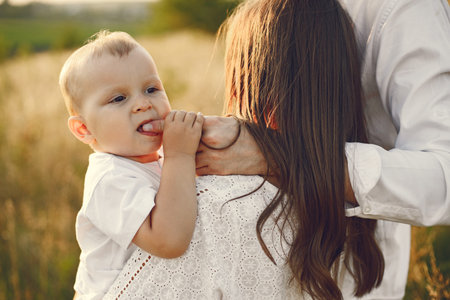 Cropped photo of a little boy with his mother and father in white clothes on the field