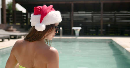 Woman in santa hat celebrate christmas at poolの写真素材