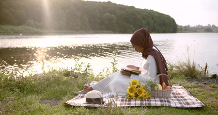 Black woman in white dress reading at the river bank