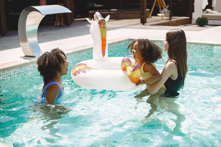 Two african american daughters and their caucasian mother swimming in the poolの写真素材