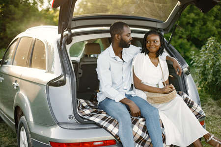 Lovely african couple sitting in a car trunkの写真素材
