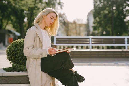 Blonde in a summer city with cup of coffeeの写真素材