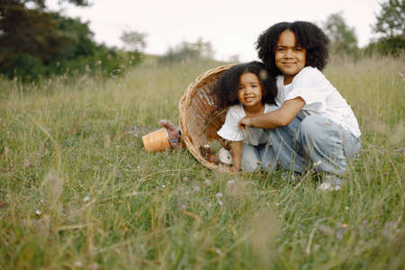 Two african baby sisters in wicker basket with toys outdoor at summertimeの写真素材