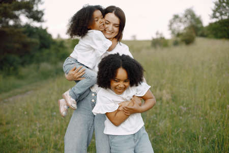 Caucasian mother embracing her mixed race daughtersの写真素材