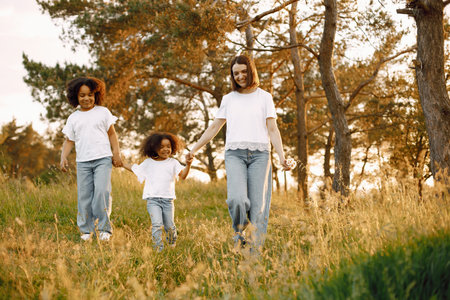 Caucasian mother and two her mixed race daughters walking in a parkの写真素材