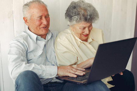 Elegant old couple sitting at home and using a laptop