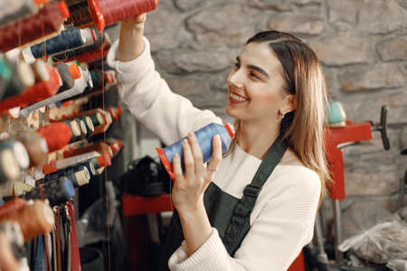 Woman tailor choosing colored spools of thread for sewing and embroideryの写真素材
