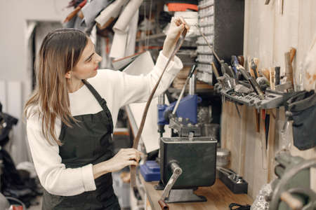 Female leather craftsman working on a beltの写真素材