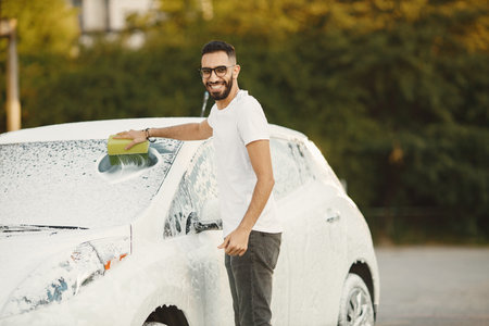 Indian man washing his white transportation on car washの写真素材