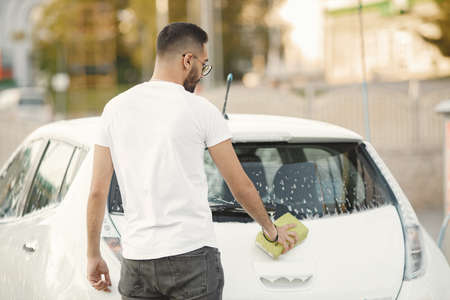 Indian man washing his white transportation on car washの写真素材