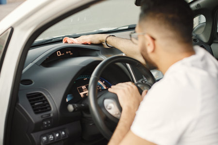 Indian man polishing his white car inside with a rug