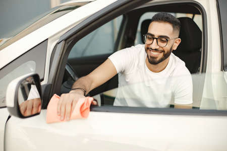 Indian man polishing inside his white car with a rugの写真素材