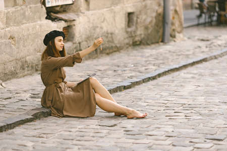 Girl in dress and black hat measuring a size of an object for drawingの写真素材